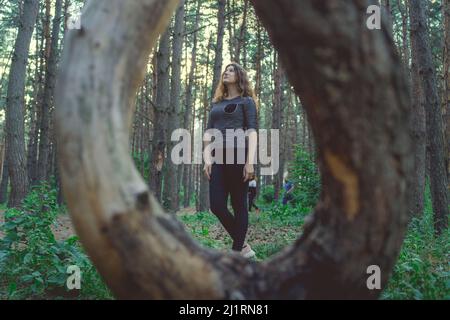 Wooden ring from tree and thoughtful woman standing in forest looking up Stock Photo