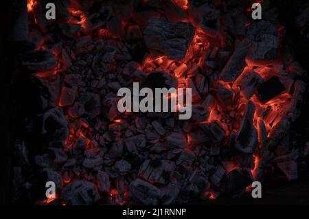 Actively smoldering embers of fire. Background of burning hot coals. Flicker of burning coals at night Stock Photo