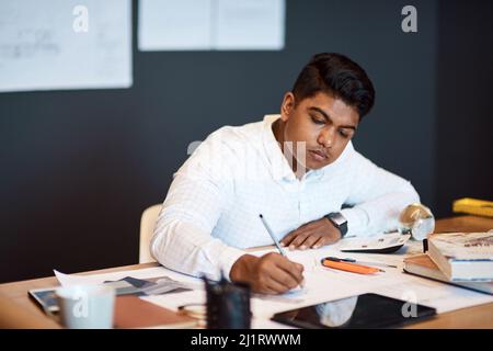 Taking his architectural business places with his technical mind. Shot of a young architect drawing up a building plan in a modern office. Stock Photo