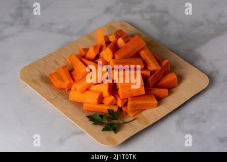 Carrots diced in big pieces  on bamboo plate over marble background - healthy eating concept Stock Photo