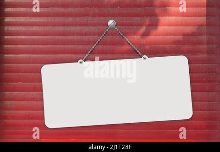 White signboard hanging on red shutter. Advertisement. Stock Photo