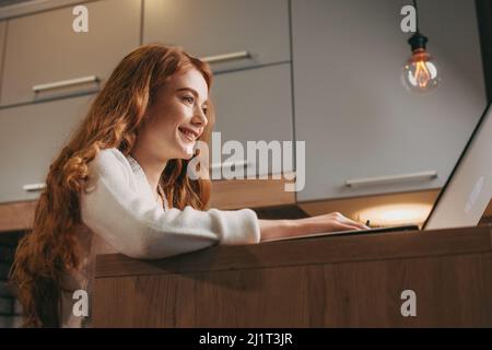 Close up side view of a caucasian redheaded woman smiling and looking at laptop screen getting ready for work. Businesswoman portrait. Business Stock Photo