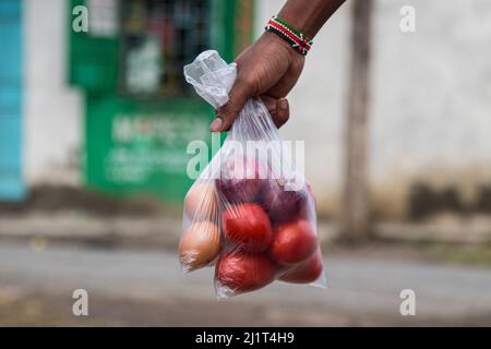 A young man is seen carrying vegetables and eggs packed in banned plastic bags and risking arrest for flouting the law. On August, 28 2017 Kenya banned the use, manufacture, and importation of all single-use plastic bags used for commercial and household packaging. The ban hailed as strictest in the world has unfortunately been frustrated by traders smuggling the bags through Kenya's porous borders with its East African neighbors. Environmental groups have been campaigning for a regional single-use plastic ban to curb increasing plastic pollution. Stock Photo