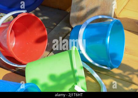 Multicolored empty clean plastic tableware on a wooden background, outdoors, on a sunny summer day. Stock Photo