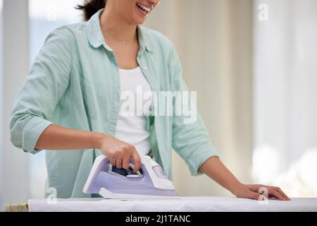 Im going to look stunning in this. Shot of a happy woman ironing her clothing. Stock Photo