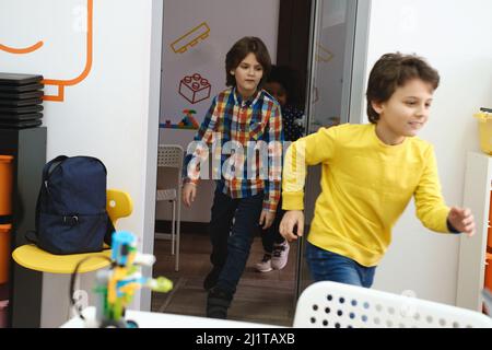 Children pupils running in school room on the brake. Happy kids having fun in elementary school. Modern education  Stock Photo