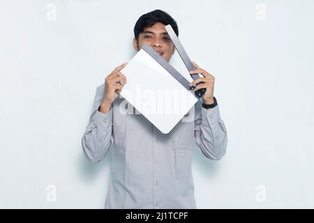 Young smiling happy asian man holding white film making clapperboard isolated on white background Stock Photo