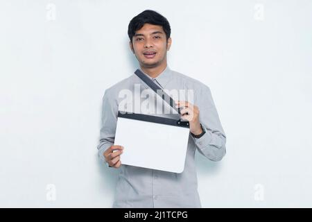 Young smiling happy asian man holding white film making clapperboard isolated on white background Stock Photo