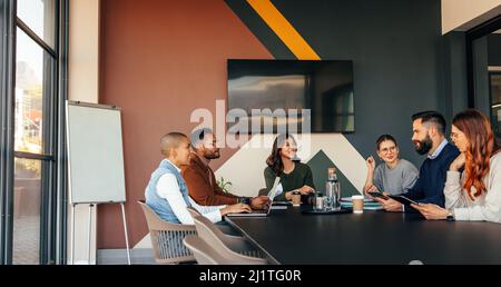 Group of multicultural businesspeople having a meeting in a boardroom. Happy businesspeople having a discussion during their morning briefing. Young e Stock Photo