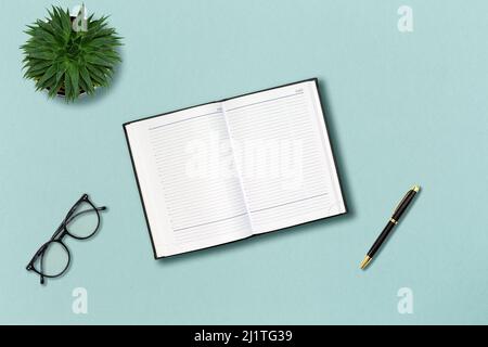 Office template. Eyeglasses, notepad, pen and succulent on the mint color background. Flat lay. Concept of education. Stock Photo