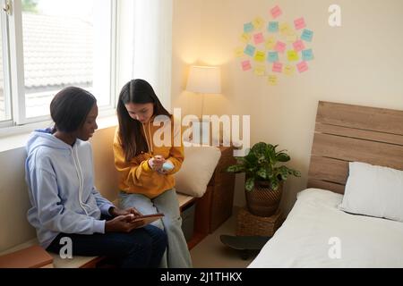 College students watching educational video on tablet computer and writing down important details on sticky notes Stock Photo