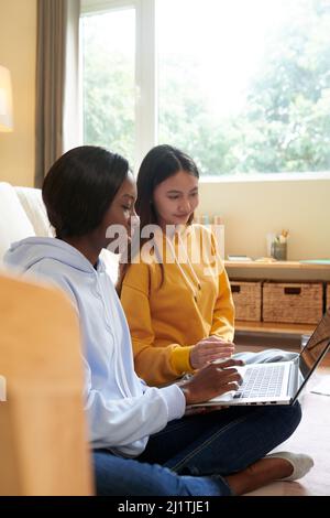 College students coding on laptop together when working on big project Stock Photo