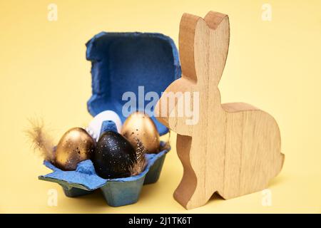 Wooden rabbit and colored eggs on yellow background, Happy Easter card Stock Photo