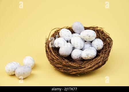 Nest with small eggs on yellow background, Happy Easter card Stock Photo