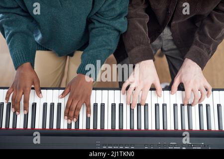 High angle view of multiethnic couple playing the synthesizer together during lesson Stock Photo