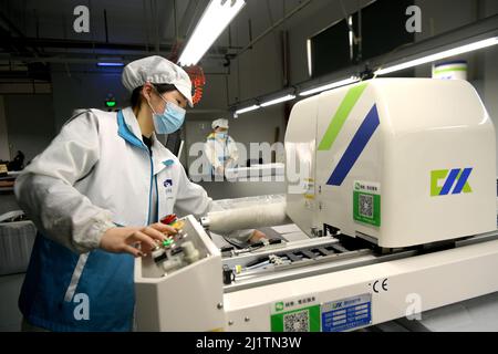 NANTONG, CHINA - MARCH 28, 2022 - Workers rush to make masks at a protective mask production workshop in Nantong, East China's Jiangsu Province, March Stock Photo