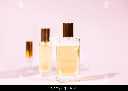 Three glass transparent rectangular bottles of golden perfume on pink background. Minimal style perfumery template. Copy space Stock Photo