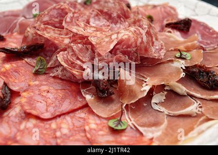 Sliced meat on a white plate, on a dark background. sausage, jamon Stock Photo