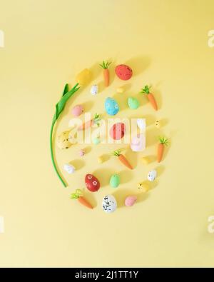 Creative Easter concept one big egg made of Easter decoration carrots and small eggs. Flat lay on pastel yellow background. Stock Photo