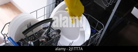 Loading dishes into the dishwasher, plate, fork, spoon Stock Photo