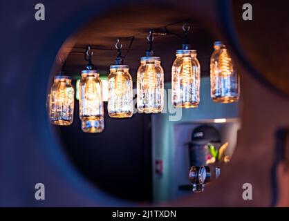 Industrial pub interior with cosy hanging lights in glass boxes through a circular mirror. Industrial interior architecture design with ceiling lights Stock Photo