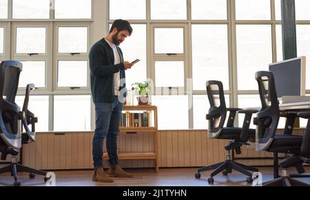 Young businessman checking his phone while standing in an office Stock Photo