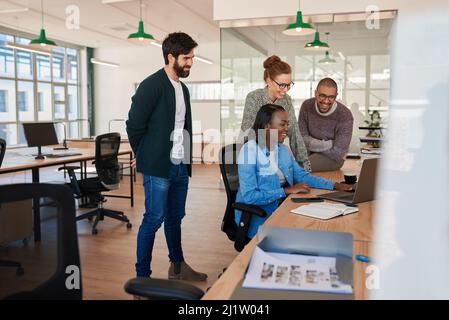 Smiling group of diverse businesspeople working together around a laptop Stock Photo