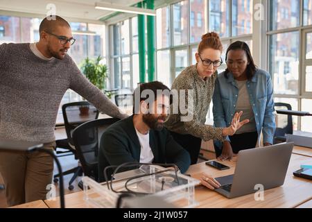 Focused group of diverse businesspeople working together on a laptop Stock Photo