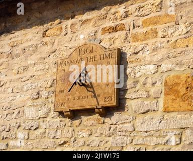 Sundial with the inscription 1961 Improve The Time, on the stone wall of an old cottage, Courteenhall, Northamptonshire, UK Stock Photo