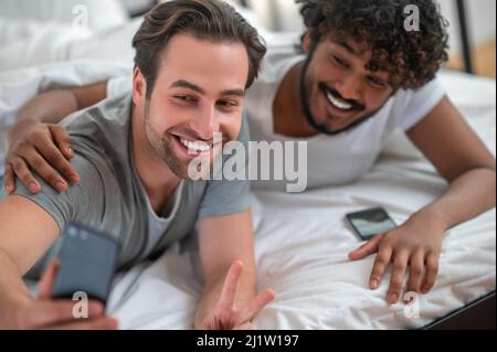 Cheerful young biracial gay couple taking selfies Stock Photo