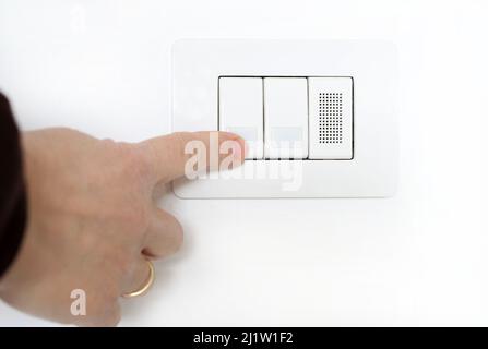 Close-up of woman finger is turning on or off the light switch. Electricity saving, energy. Stock Photo
