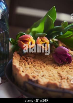 Homemade cake sprinkled with cookie crumbs on a metal vintage dish, decorated with tulips.  Stock Photo