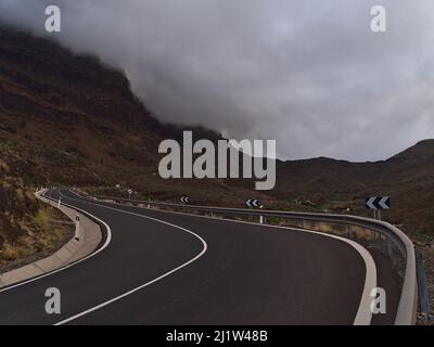 View of remote country road GC-200 in the west of Gran Canaria, Canary Islands, Spain near village La Aldea de San Nicolas surrounded by mountains. Stock Photo