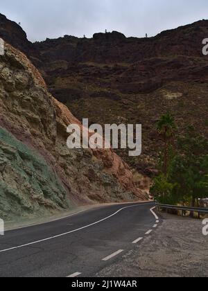 Landscape with colorful volcanic rocks at Los Azulejos De Veneguera in the western mountains of Gran Canaria, Canary Islands, Spain with rural road. Stock Photo