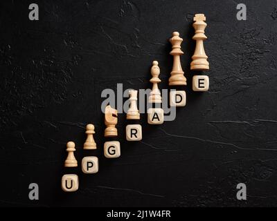 The word upgrade on wooden cubes with chess pieces. Technology or business update or upgrade concept. Stock Photo