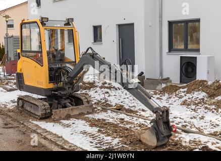 Small excavator parked in front of a new building Stock Photo