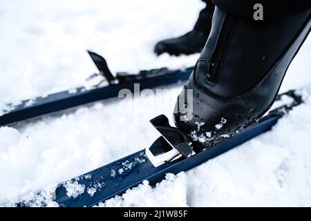 From above of crop unrecognizable person in black boots standing on skis on snow in winter Stock Photo