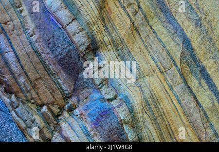 From below of massive rocky cliff with striped pattern in daytime as abstract background Stock Photo