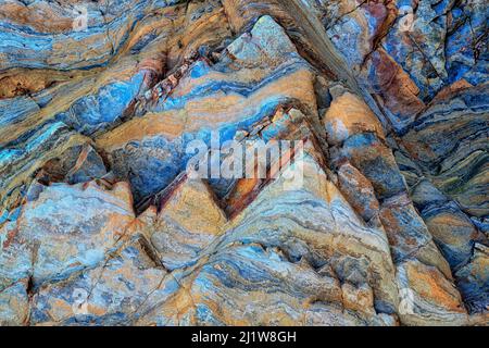 Closeup uneven surface of blue colored rough stone with geometric pattern and cracks as textured background Stock Photo