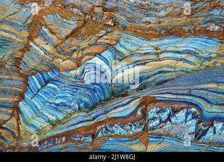 From below of massive rocky cliff with striped pattern in daytime as abstract background Stock Photo