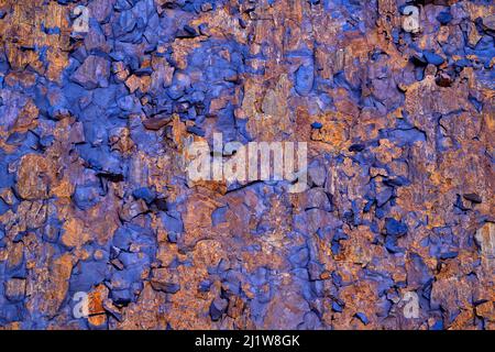 Abstract background of uneven weathered two colored rocky wall with rust and textured surface Stock Photo