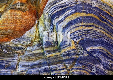 From below of massive rocky cliff with striped pattern in daytime as abstract background Stock Photo