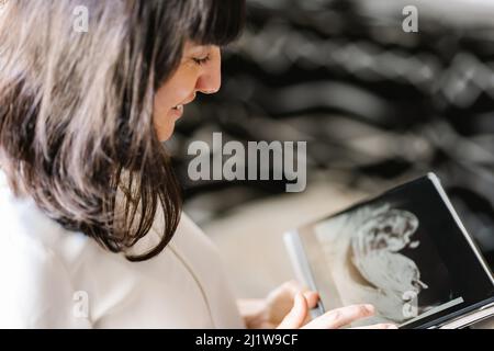 From above of cheerful pregnant mother looking at ultrasound scan of unborn baby on digital tablet Stock Photo