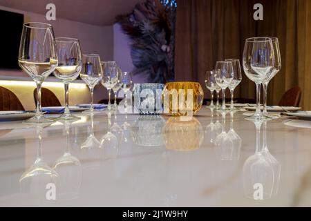 Crystal wineglasses served on banquet table with ceramic plates and flatware for celebration in dining room Stock Photo
