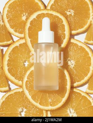 Top view of vial with natural Hyaluronic acid serum for skin care routine placed on orange slices in light room Stock Photo