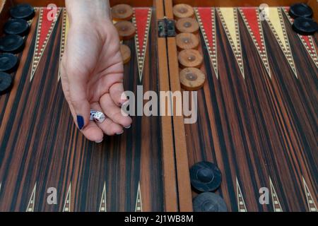 Close up woman hand holding backgammon dices and playing backgammon at outside. The focus is on her hand. Stock Photo