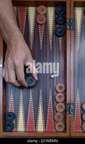 Close up woman hand holding backgammon dices and playing backgammon at outside. The focus is on her hand. Stock Photo