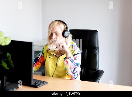 Portrait of serious focused middle-aged woman wearing headphones watching webinar at office computer Stock Photo