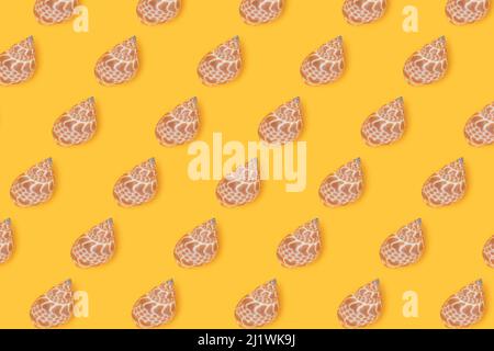 Repetitive pattern made from seashells. Creative layout on a yellow background. Summer concept. Stock Photo