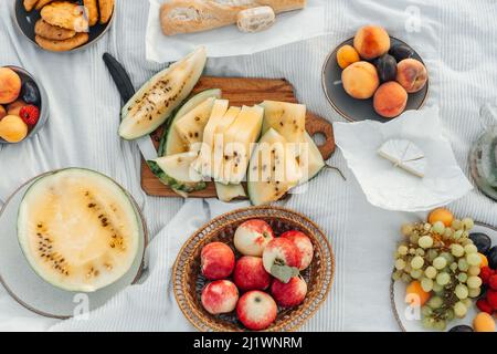 Various Fruits and cheese on white blanket, picnic outdoor. Stock Photo